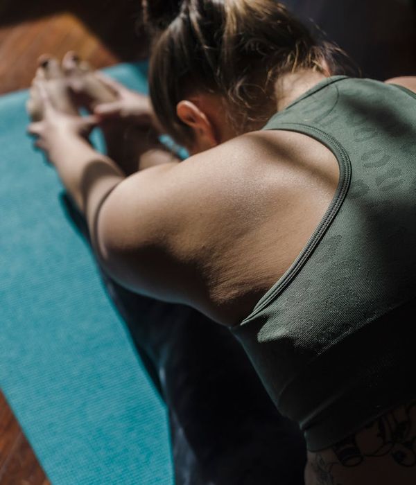 Woman performing a calm yoga pose in a dark room.